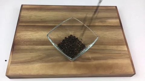 Black pepper falling in a transparent dipping glass bowl Stock Footage 124383739