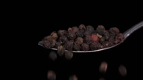 Black pepper peas falling from the iron spoon, black background, slow motion Vidéo 74726314