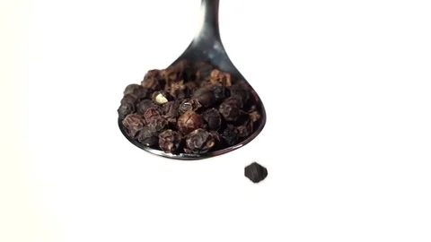 Black pepper peas falling from the iron spoon. White background. Slow motion Vidéo 75523873