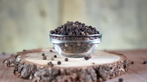 Black pepper in peas in a glass socket on a wooden stand rotates Video stock 137867412