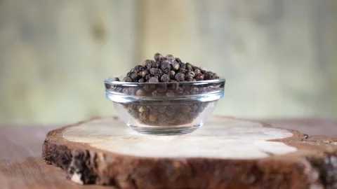 Black pepper in peas in a glass socket on a wooden stand rotates Video stock 137867459