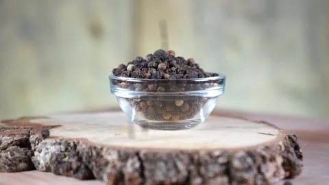 Black pepper in peas in a glass socket on a wooden stand rotates Stock Footage 144360433