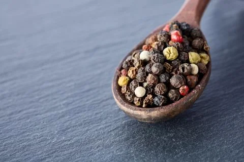 Black pepper peas in a spoon on a stone background Stock Photos