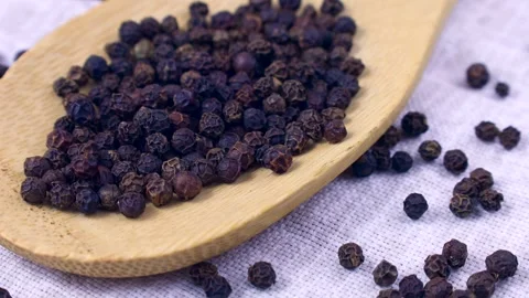 Black pepper peppercorns falling down into the spoon close up Stock Footage 270475794