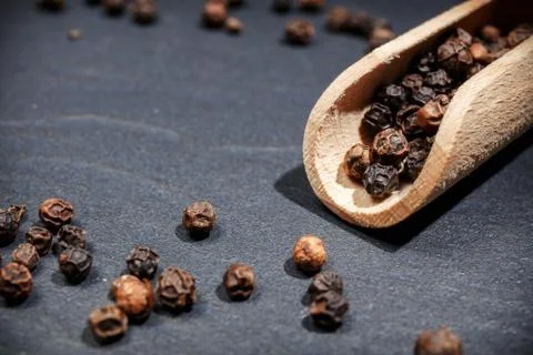 Black pepper on rustic stone background. Overhead view food photography. Stock Photos
