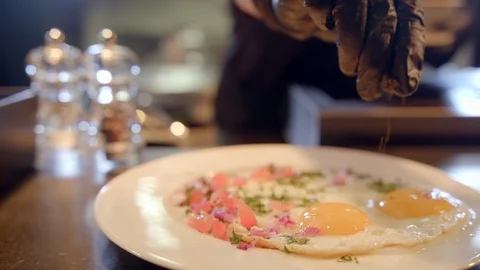 Black pepper sprinkled on fried eggs in restaurant Stock Footage 99400421