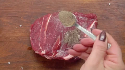 Black pepper sprinkled on a piece of raw beef Stock Footage 294410436