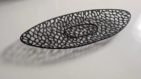 Black perforated oval decorative dish with shadow on white background Stock Photos