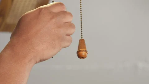 Black person turning fan on and off by pulling chain Stock Footage 135850853