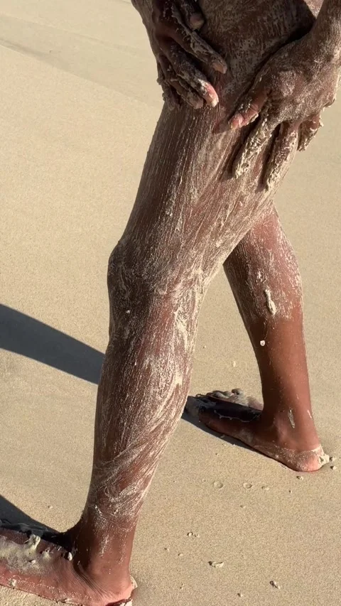 Black person using sand to exfoliate their skin on the beach Stock-Footage 305129352
