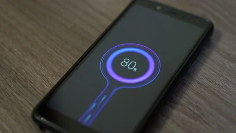 A black phone is charging at the edge of the table Stock Footage 130273850