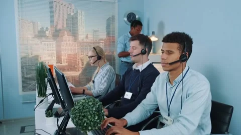 Black phone operator helping his colleague in call center Stock Footage 130660681