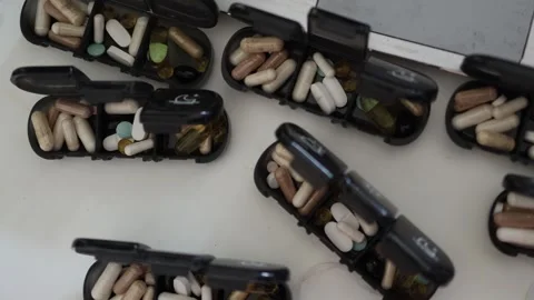 Black pill organizers filled with assorted vitamins and dietary supplements incl Stock Footage 314519214