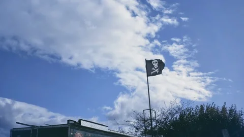 Black pirate flag flutter on wind with partly overcast blue sky. Stock Footage 92146942