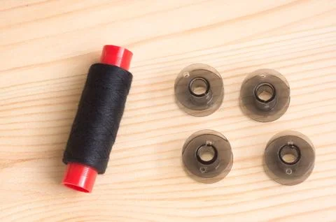 Black plastic bobbin for sewing machine. and  threads on a wooden background Stock Photos