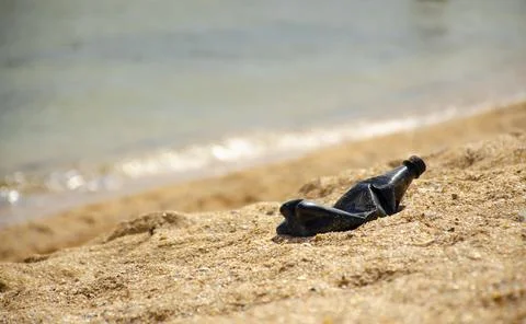 Black plastic bottle or garbage on beach of sea with the backdrop of the sea  Stock-Fotos