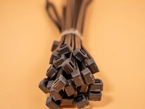Black plastic cable ties on an orange background. Stock Photos