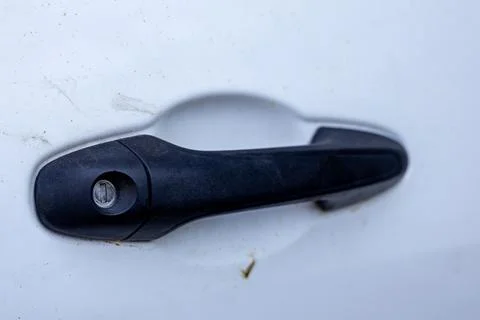 Black plastic car door handle with key cylinder on dirty white vehicle door. Stock Photos