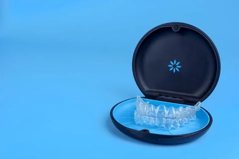 Black plastic case with transparent braces on blue background. Insivible Stock Photos