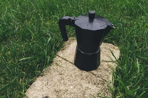 Black plastic coffee maker on green grass background. Selective focus Stock Photos