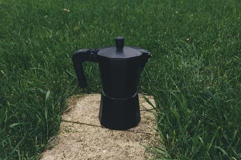 Black plastic coffee maker on green grass background. Selective focus Stock Photos