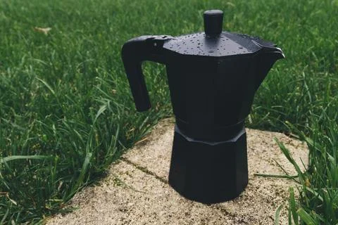 Black plastic coffee maker on green grass background. Selective focus Stock Photos