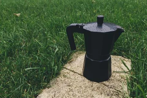 Black plastic coffee maker on green grass background. Selective focus Stock Photos