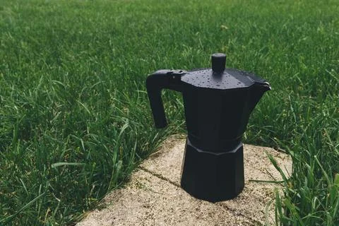 Black plastic coffee maker on green grass background. Selective focus Stock Photos