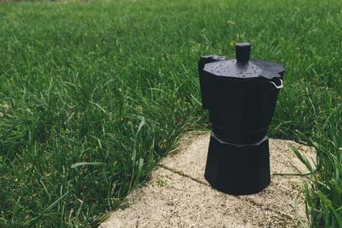 Black plastic coffee maker on green grass background. Selective focus Stock Photos