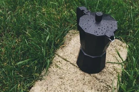 Black plastic coffee maker on green grass background. Selective focus Stock Photos