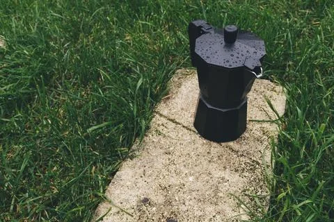 Black plastic coffee maker on green grass background. Selective focus Stock Photos