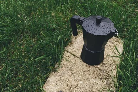 Black plastic coffee maker on green grass background. Selective focus Stock Photos