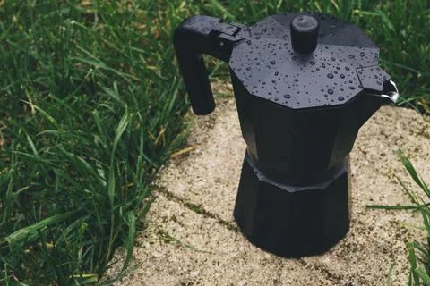 Black plastic coffee maker on green grass background. Selective focus Stock Photos