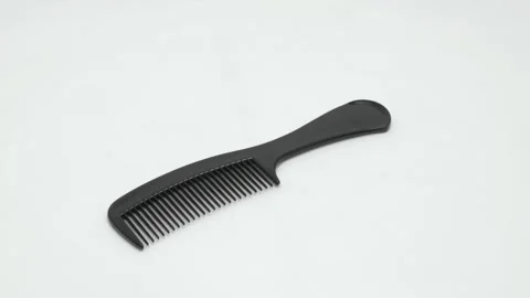 A black plastic comb rotates on a white background. Видео 268990610