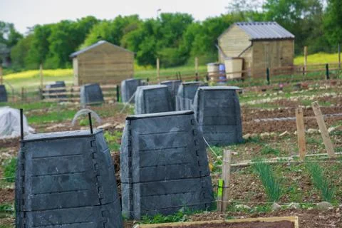 Black plastic compost bin and small wooden cabin in town garden Stock Photos