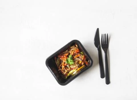 Black plastic container with vegetables stir fry and black appliances Stock Photos