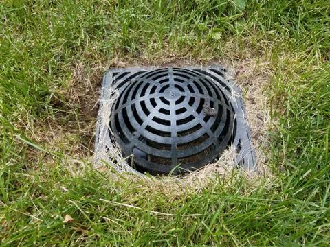 Black plastic drain in green grass or lawn Stock Photos