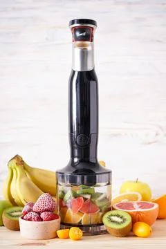Black plastic electrical hand blender and accessories with sliced fruit on a  Stock Photos