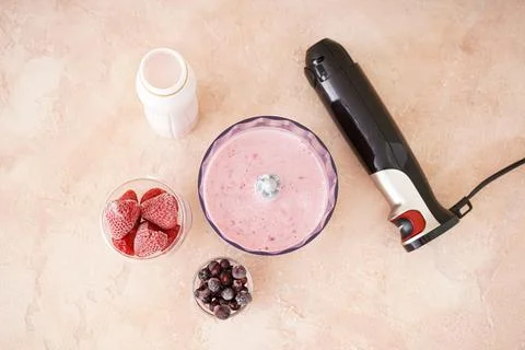 Black plastic electrical hand blender and accessories with fruit on color bac Stock Photos