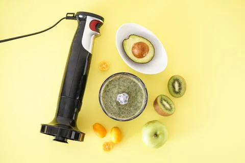 Black plastic electrical hand blender and accessories with fruit on a yellow  Stock Photos