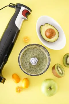 Black plastic electrical hand blender and accessories with fruit on a yellow  Stock-Fotos