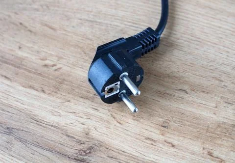 Black plastic electrical power plug with metal pins lying disconnected on a.. Foto stock