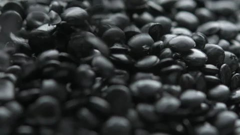 Black plastic pellets pour from above onto resin granules pile in macro view, Stock Footage 334659479
