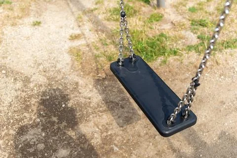 Black plastic swing on chains, no backrest, playground 写真素材