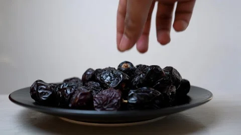 Black plate filled with fresh dates on a white background Stock Footage 318125124