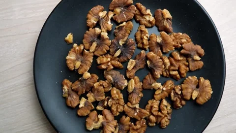 Black plate filled with shelled walnuts on a wooden table Stock Footage 320727316