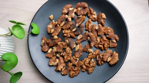 Black plate filled with shelled walnuts on a wooden table Stock Footage 320727341