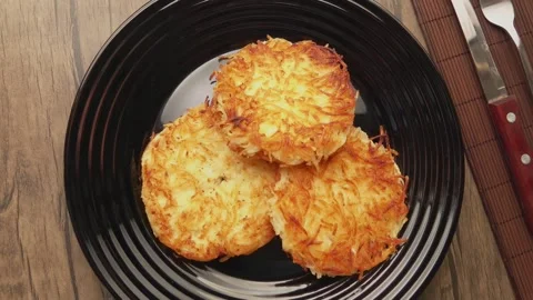 A black plate with ready-made fried potato pancakes is placed on the table Video stock 279308574