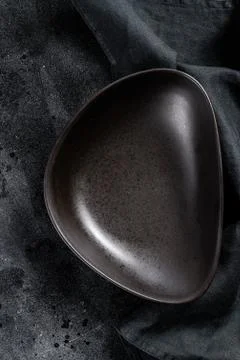 Black plate triangular shape on textured black background. Top view. Copy space Foto stock