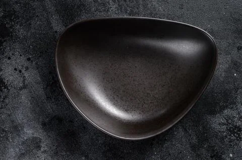 Black plate triangular shape on textured black background. Top view. Copy space Stock Photos